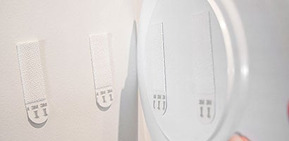Command medium picture hanging strips are applied to a  lightweight melamine plate
