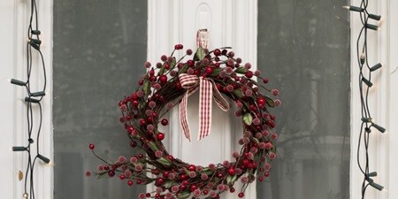 Lights frame the window, which is decked in Christmas-red wreath
