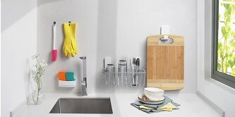 Cleaning gloves, a dish brush, and a cutting board are hung on Command hooks, while sponges are placed in an organizer.
