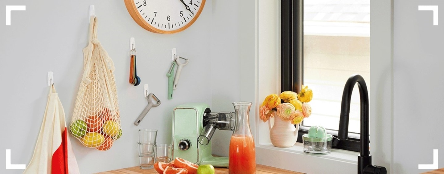 Vegetables in bags, measuring spoons, and fruit knives are hung using Command hooks.
