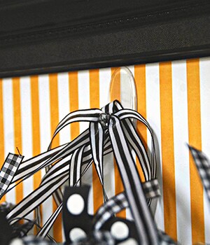 Adhere a Command™ Clear Medium Hook inside a black picture frame with orange patterned scrapbook paper inside
