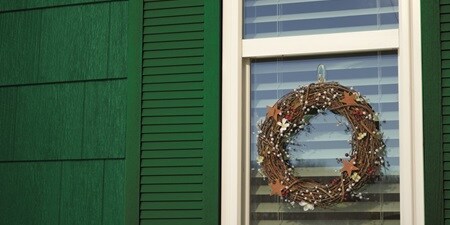 Woodsy themed Christmas wreath  hanging on a clear glass window using Command Outdoor Clear Hook
