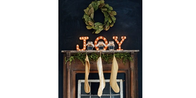 Create a temporary holiday mantel featuring a wreath, the word 'JOY,' Mason jars, and Christmas stockings, all arranged using Command hooks.