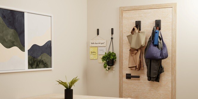 Entryway nook: tote bags and jacket hanging on black Command™ hooks on a timber-panelled door
