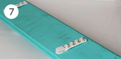 Attaching picture hanging strips to the back of the board
