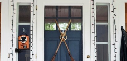 Halloween front door décor ideas: Hang string lights, signs, brooms, and fabric accents using Command™ Outdoor Light Clips and Hooks.
