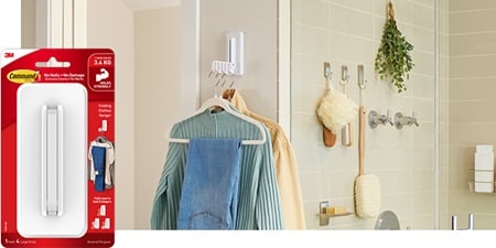 A Command folding clothes hanger is installed on the wall near the bathroom area with five hangers.
