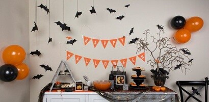 Paper bats, orange and black banners, balloons, and other Halloween party decorations hung with Command™ Clear Hooks and Decorating Clips. 
