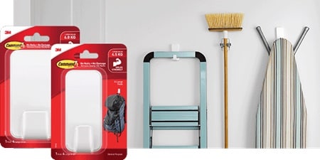 Ladder, brooms, and ironing pad hung on the wall with Command heavy duty hooks and broom gripper

