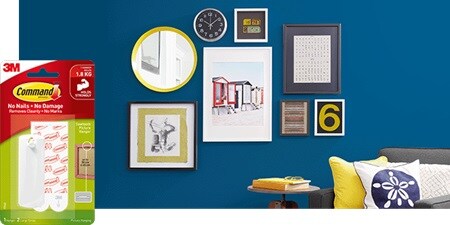 A stylish wall decorated with clocks and artworks using Command picture hanging strips and sawtooth picture hangers.
