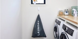 A laundry bag filled with clothes hung on the wall with a Command heavyweight hook
