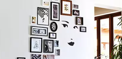A unique wall display featuring a face wall decal surrounded by picture frames mounted with Command picture hanging strips.
