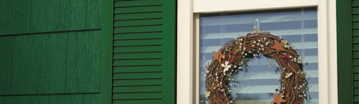 A Christmas wreath is hung on the window glass using a Command outdoor clear window hook
