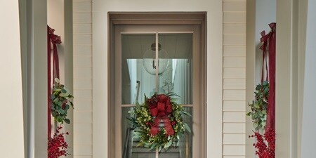This neutral-toned home gets a touch of red, thanks to the lovely wreaths and other outdoor decors
