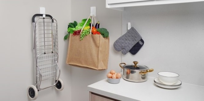 Shopping cart and a bag full of groceries hung on the wall with Command heavyweight hooks

