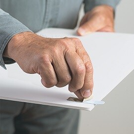 Person applying Command Picture Hanging Strip on the back of a photo frame