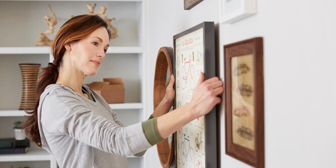 Woman arranging her artwork at eye level
