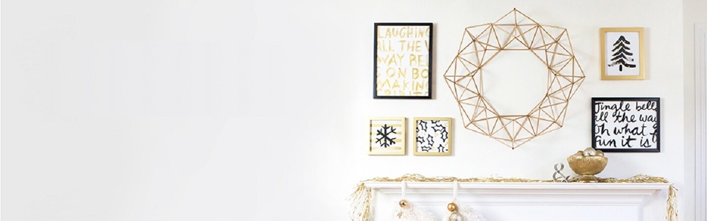 Festive Christmas artworks are displayed on the wall using Command picture hanging strips.

