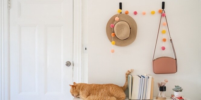 Entryway with wall hooks holding a straw hat and pink purse
