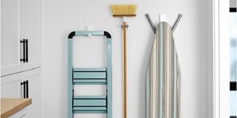 Ladder, brooms, and ironing pad hung on the wall with Command heavyweight hooks and broom gripper
